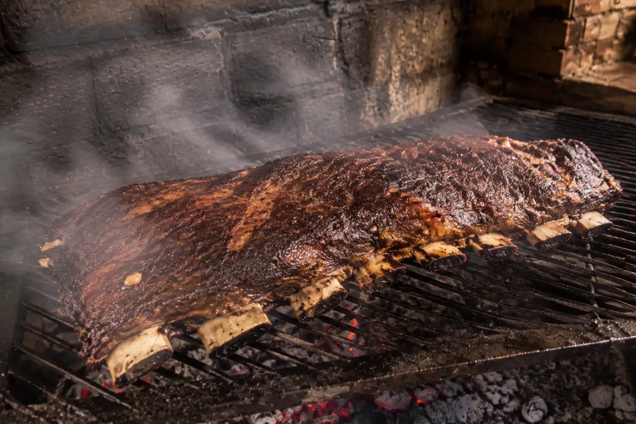 Manta desembrulhada de volta na grelha nos últimos minutos, com a superfície borbulhando, crosta brilhante se formando e a gordura pingando na brasa.